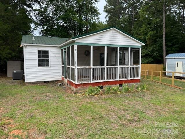 view of front of home featuring central AC, a sunroom, and a front yard