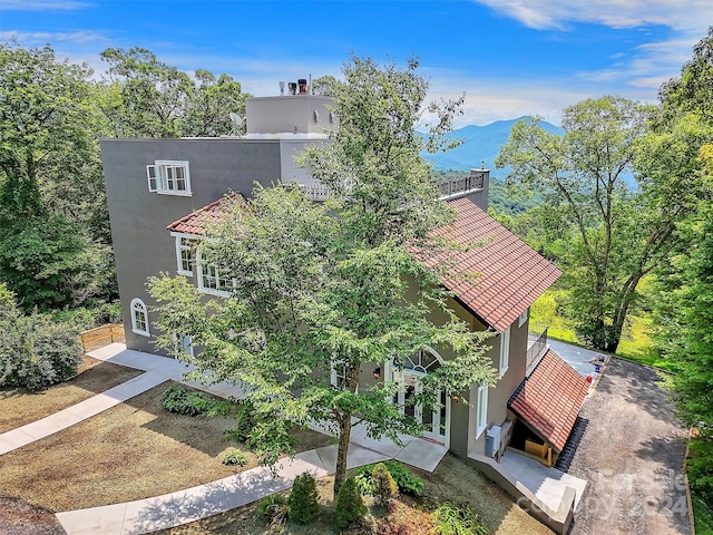 exterior space with a patio area, a tile roof, a mountain view, and stucco siding