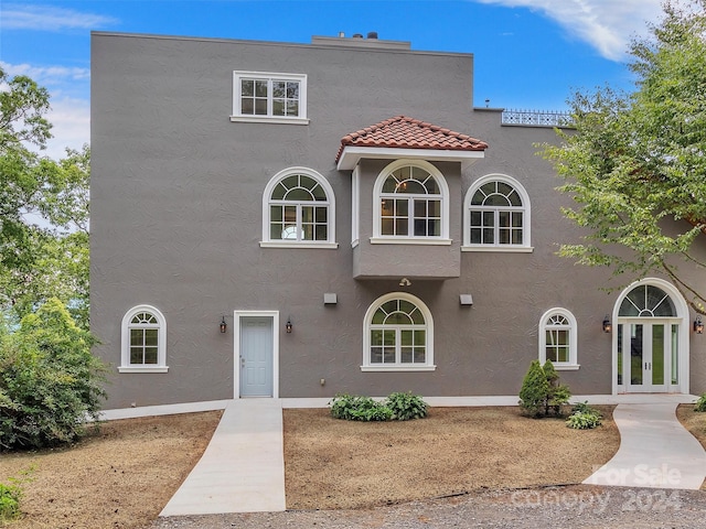 mediterranean / spanish-style house with a tiled roof, french doors, and stucco siding