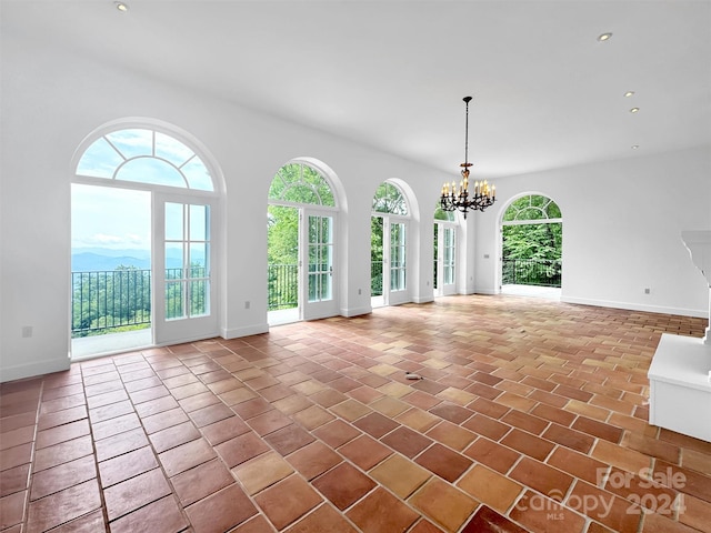 unfurnished living room featuring tile patterned floors, a healthy amount of sunlight, and a notable chandelier