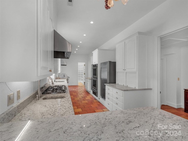 kitchen featuring extractor fan, sink, white cabinets, light stone counters, and stainless steel appliances