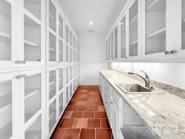 kitchen featuring white cabinetry, sink, and light stone counters