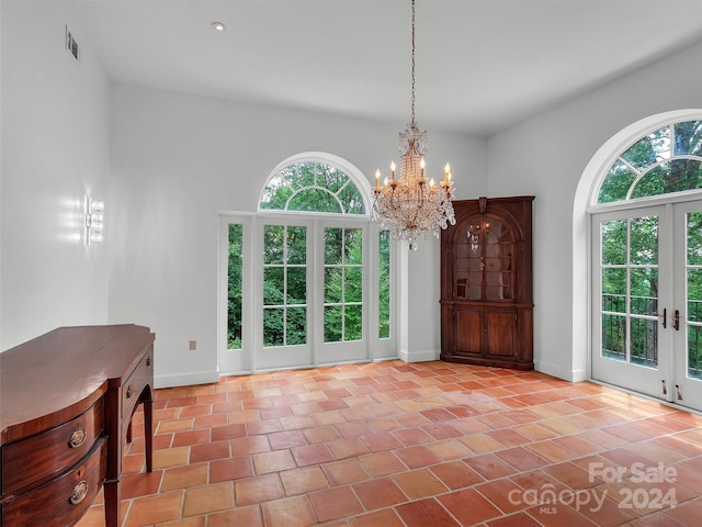 unfurnished dining area with french doors, plenty of natural light, an inviting chandelier, and light tile patterned floors