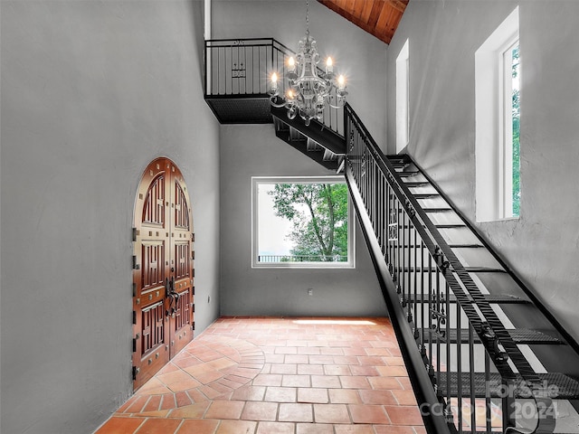 stairs featuring an inviting chandelier, high vaulted ceiling, and wooden ceiling