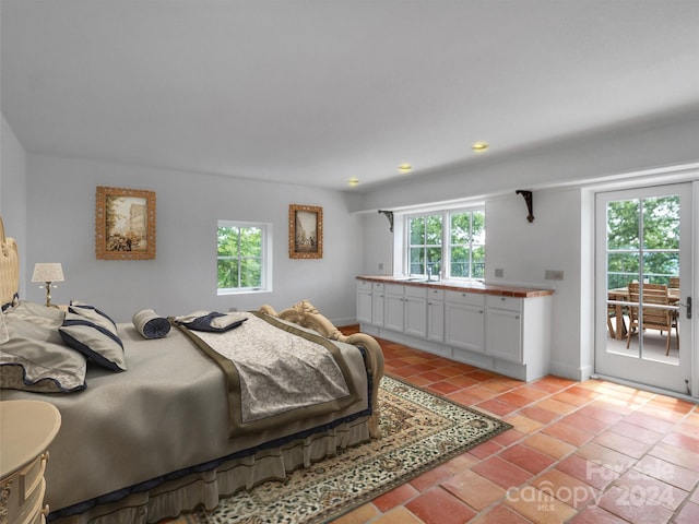 tiled bedroom with multiple windows and access to exterior