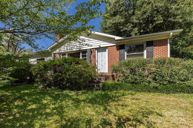 view of front facade with brick siding and a front yard