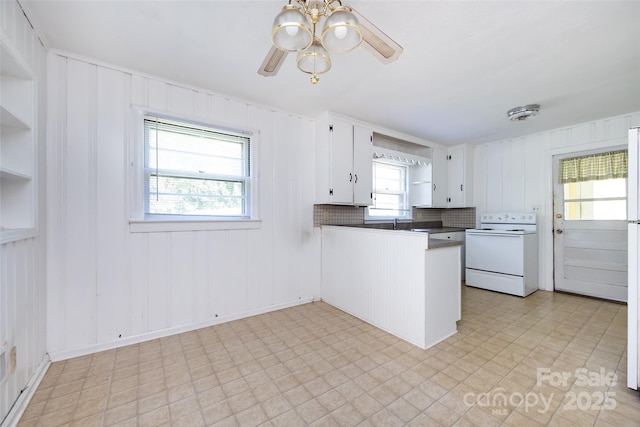 kitchen featuring white electric range, a peninsula, white cabinetry, open shelves, and dark countertops