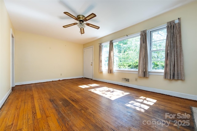 spare room with visible vents, ceiling fan, hardwood / wood-style flooring, and baseboards