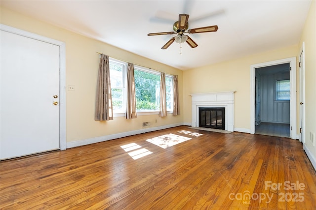 unfurnished living room with ceiling fan, a fireplace with flush hearth, hardwood / wood-style flooring, and baseboards