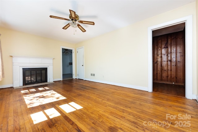 unfurnished living room with a fireplace with flush hearth, wood-type flooring, visible vents, and ceiling fan