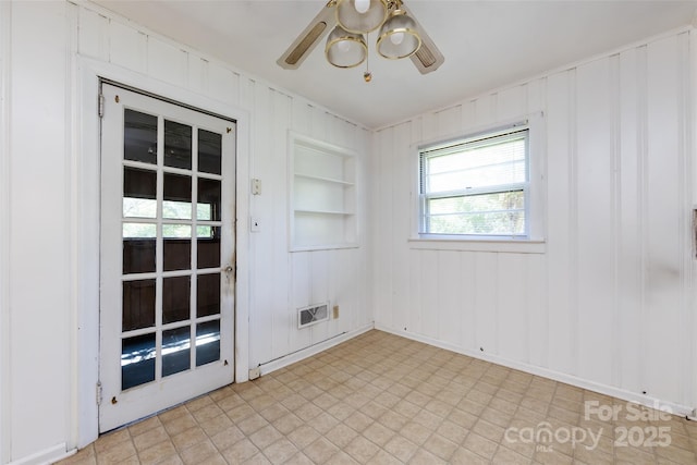 empty room featuring built in shelves, visible vents, and a ceiling fan