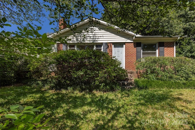 view of front of property with a front yard, brick siding, and a chimney