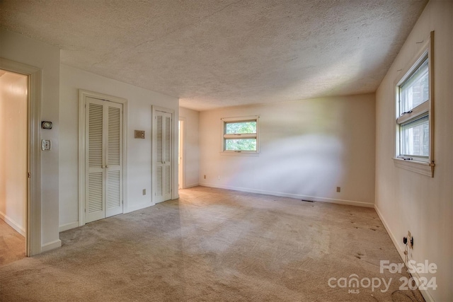 spare room with light colored carpet and a textured ceiling