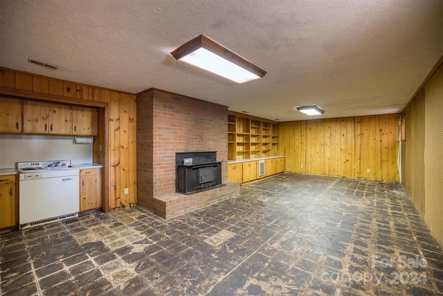 unfurnished living room with built in shelves, wood walls, a wood stove, and a textured ceiling