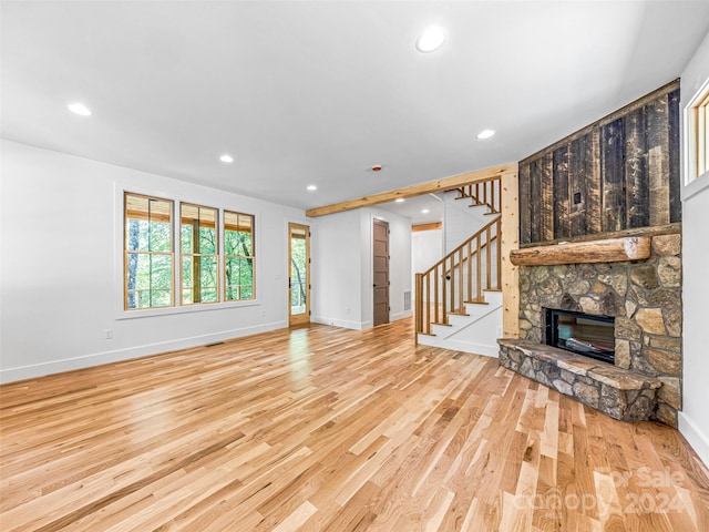 unfurnished living room with a stone fireplace and light hardwood / wood-style flooring