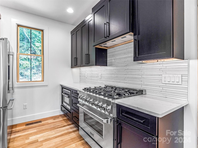 kitchen with light hardwood / wood-style floors, a healthy amount of sunlight, light stone countertops, and stainless steel appliances