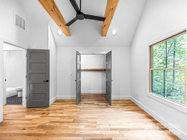 unfurnished bedroom featuring beam ceiling, light hardwood / wood-style floors, and multiple windows