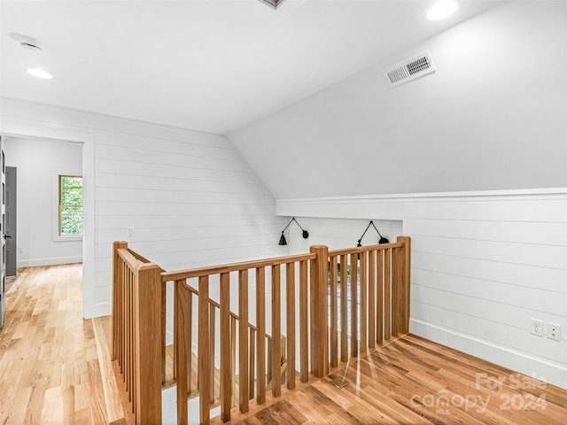 stairway with lofted ceiling and light hardwood / wood-style floors