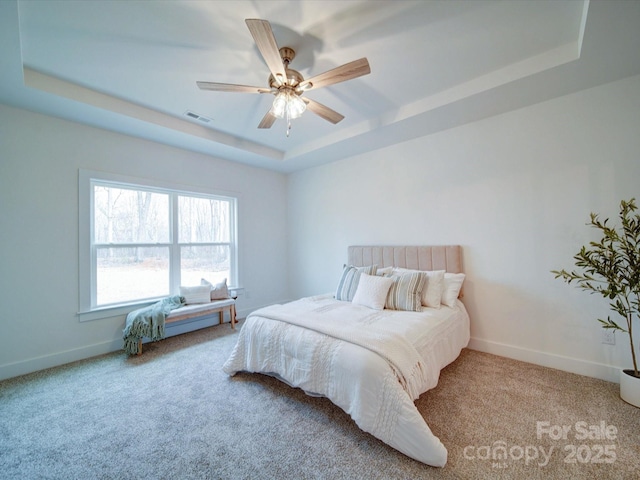 bedroom featuring light carpet, ceiling fan, and a tray ceiling