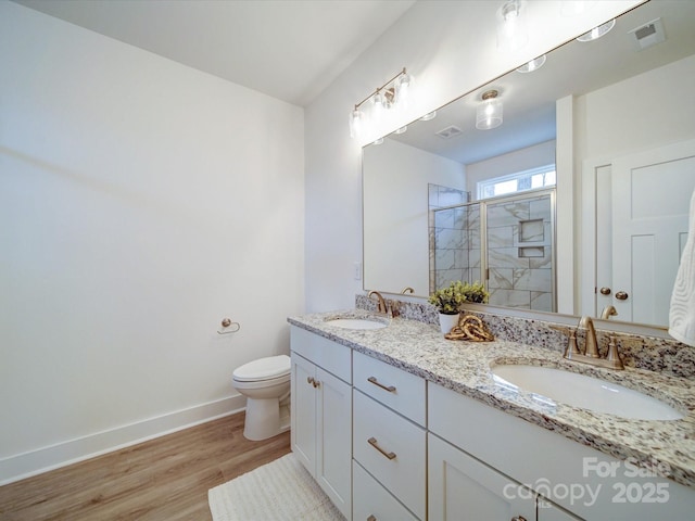 bathroom featuring wood-type flooring, toilet, a shower with door, and vanity