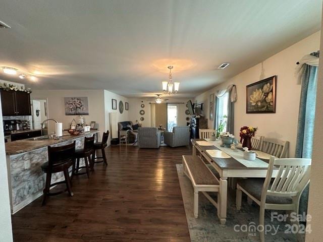 dining room with a notable chandelier, sink, and dark wood-type flooring