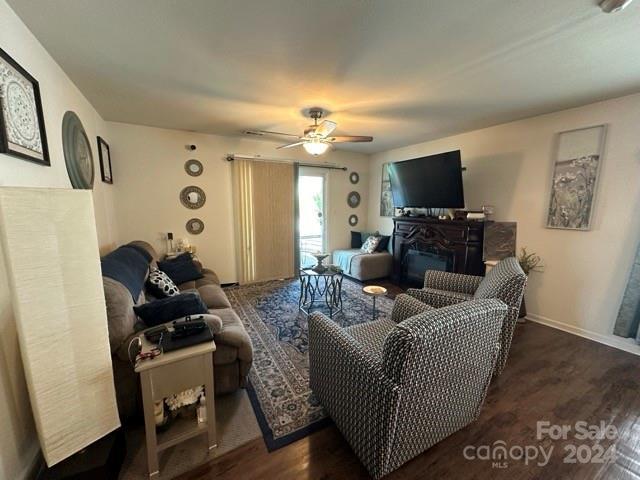 living room with a fireplace, ceiling fan, and dark hardwood / wood-style flooring