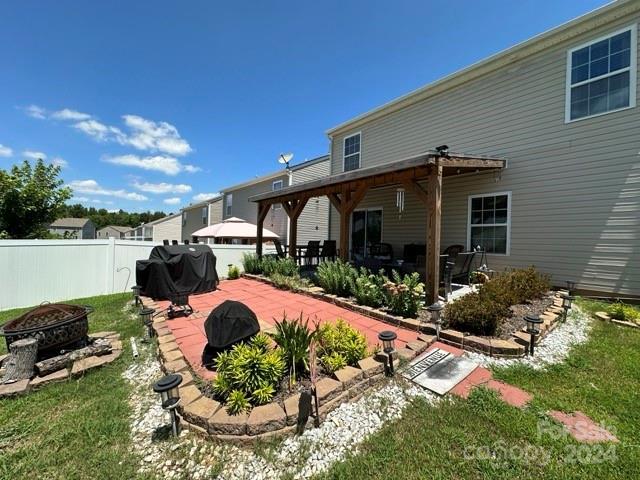 back of house featuring a lawn, a patio area, a pergola, and an outdoor fire pit