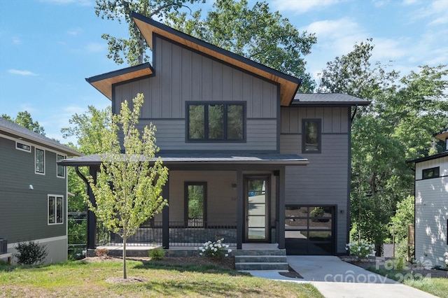 contemporary house featuring a front yard, a garage, a porch, and central air condition unit