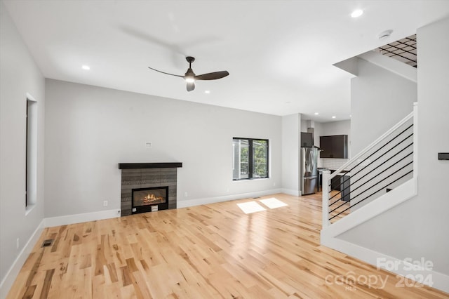 unfurnished living room featuring ceiling fan, a fireplace, and light hardwood / wood-style floors