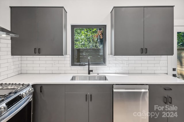 kitchen featuring decorative backsplash, sink, gray cabinetry, and stainless steel gas range