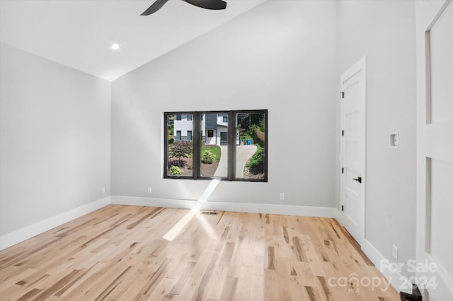 empty room with ceiling fan, high vaulted ceiling, and light hardwood / wood-style floors