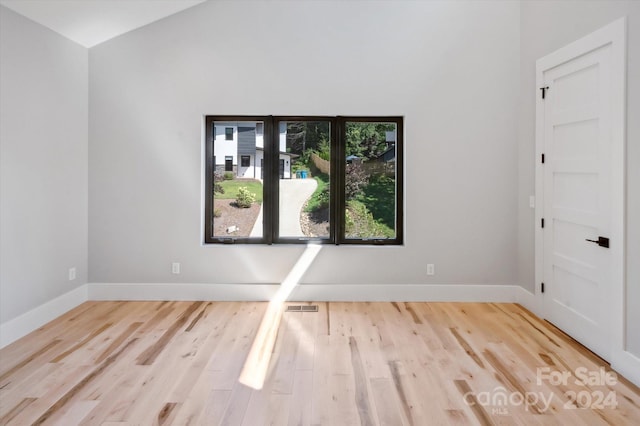 spare room featuring lofted ceiling and light wood-type flooring