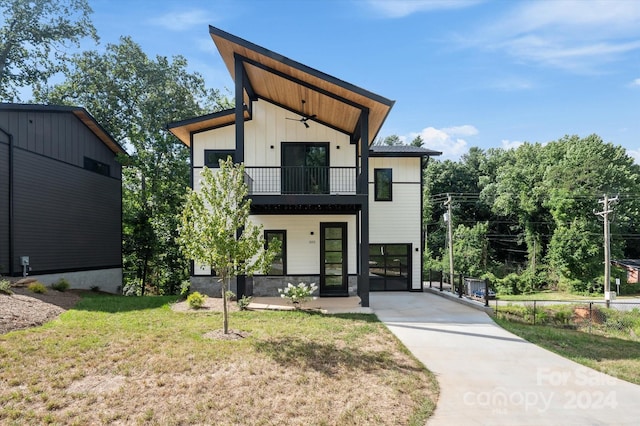 contemporary house featuring a front yard, ceiling fan, and a balcony