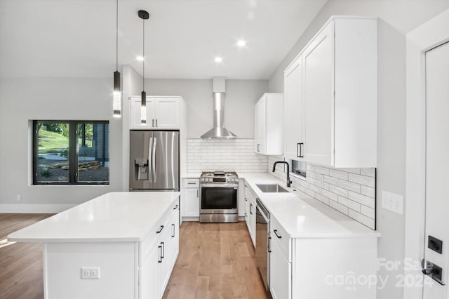 kitchen with appliances with stainless steel finishes, white cabinetry, tasteful backsplash, sink, and hanging light fixtures