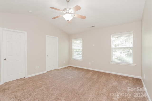 carpeted empty room with ceiling fan, a healthy amount of sunlight, and vaulted ceiling