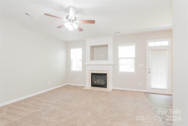 unfurnished living room featuring ceiling fan and light carpet