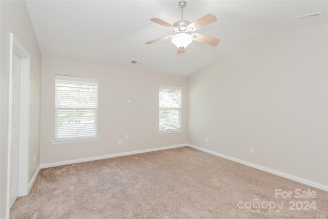 carpeted empty room with vaulted ceiling, ceiling fan, and a healthy amount of sunlight