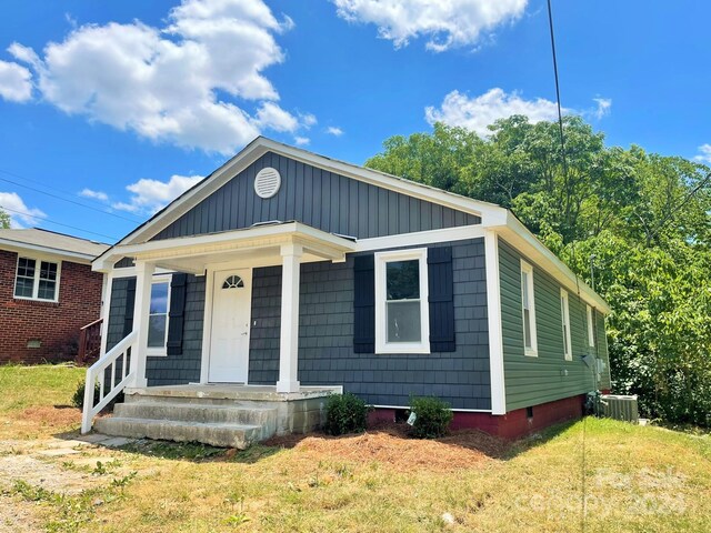 bungalow-style house featuring central AC, a porch, and a front yard