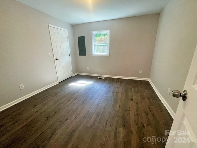 unfurnished room featuring dark wood-type flooring and electric panel