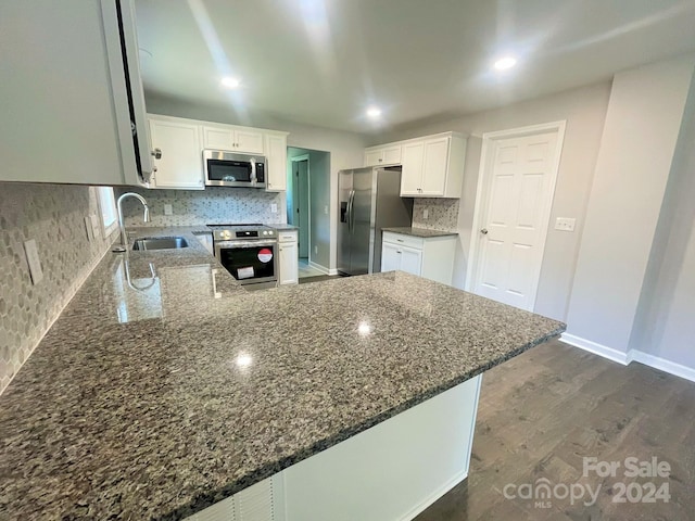 kitchen with kitchen peninsula, sink, white cabinetry, and stainless steel appliances