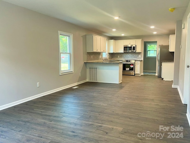 kitchen featuring white cabinetry, sink, dark hardwood / wood-style floors, kitchen peninsula, and appliances with stainless steel finishes