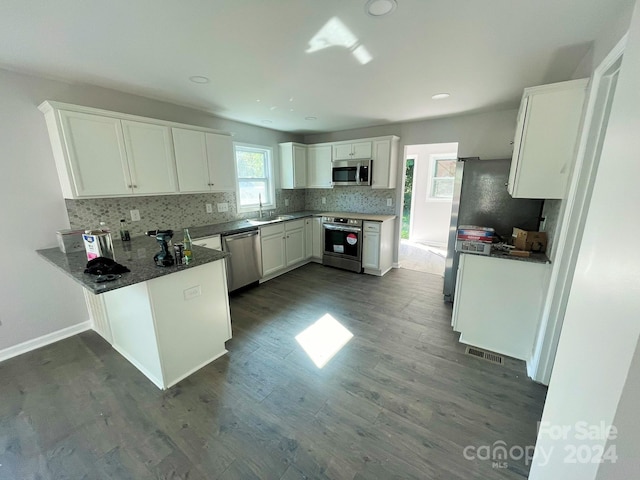 kitchen with kitchen peninsula, white cabinets, dark hardwood / wood-style floors, and appliances with stainless steel finishes