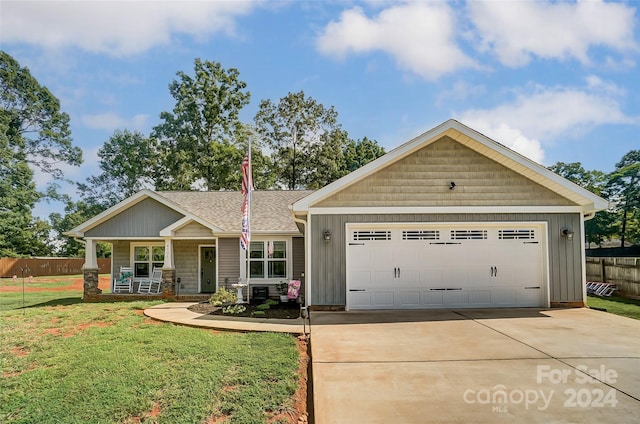 view of front of home with a front yard, a garage, and a porch