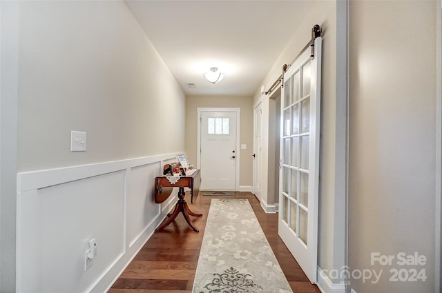 doorway to outside featuring a barn door and dark hardwood / wood-style floors