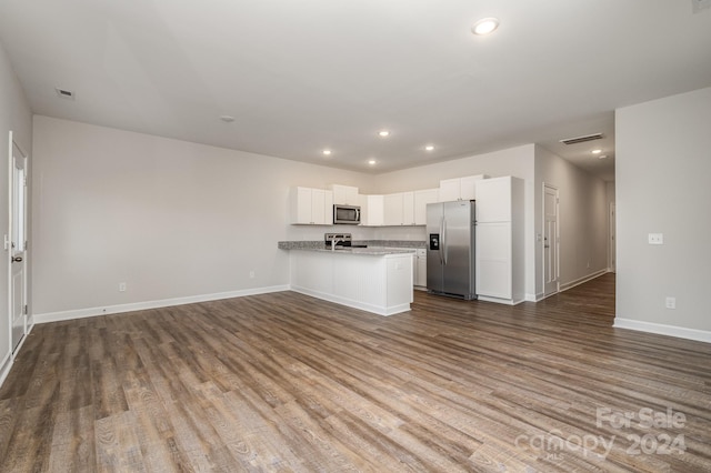 kitchen featuring stainless steel appliances, hardwood / wood-style floors, kitchen peninsula, light stone countertops, and white cabinetry