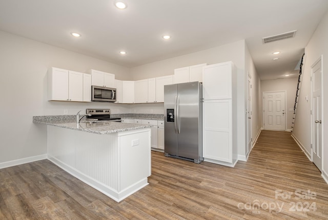 kitchen with white cabinetry, appliances with stainless steel finishes, kitchen peninsula, and light hardwood / wood-style floors