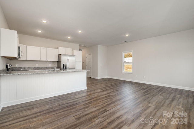 kitchen featuring white cabinetry, light stone counters, stainless steel fridge, and range