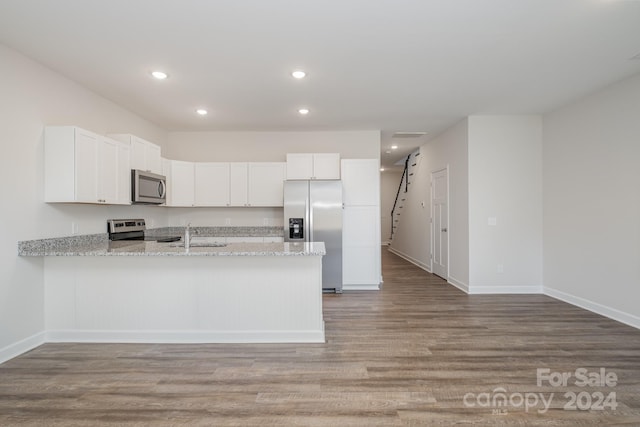 kitchen with stainless steel appliances, light stone countertops, white cabinets, and kitchen peninsula