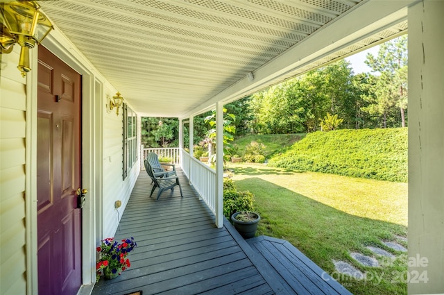 wooden terrace featuring a porch and a lawn