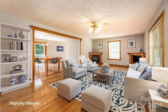 living room with a textured ceiling, ceiling fan, light wood-type flooring, and a wealth of natural light